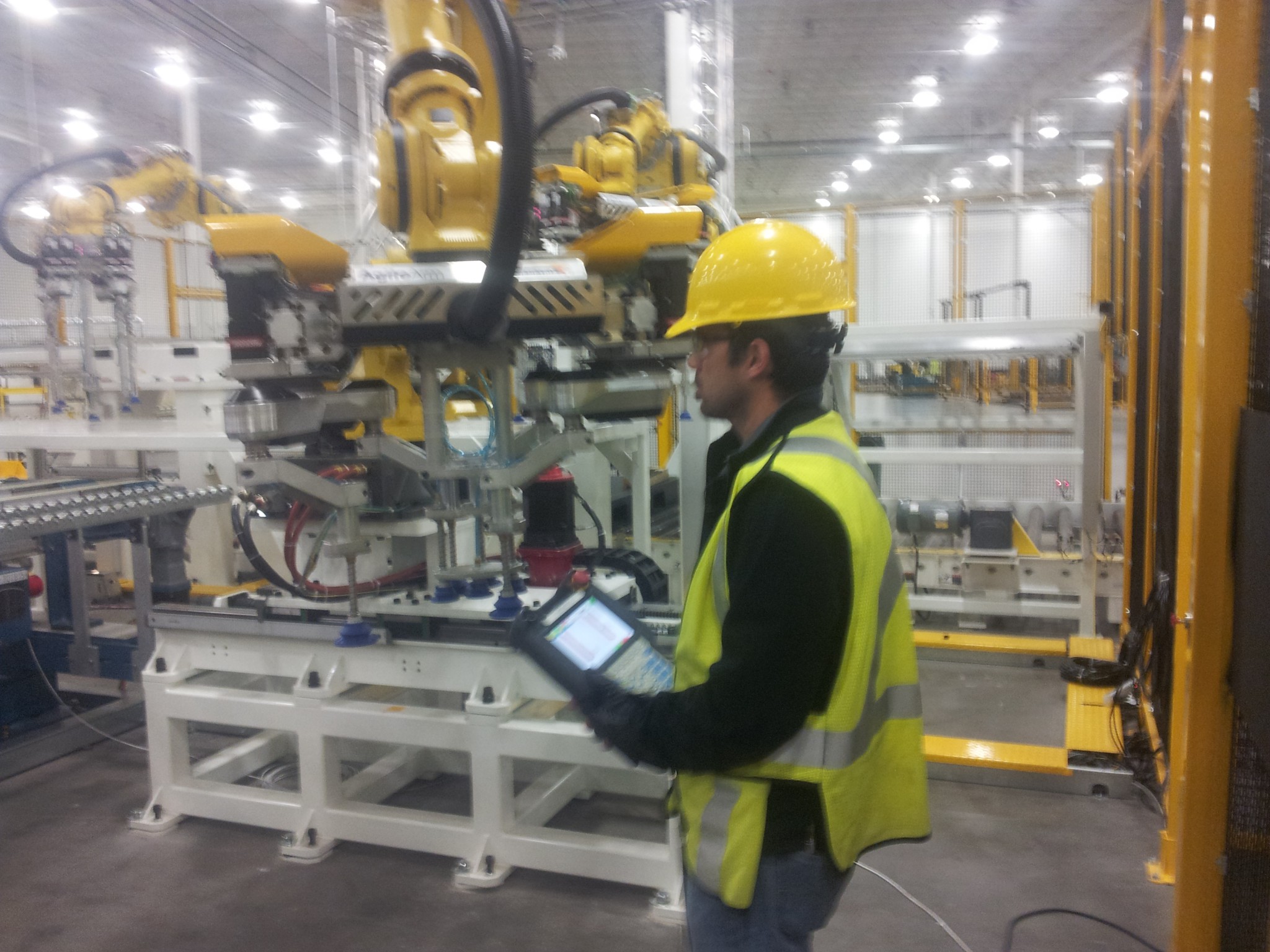 Engineer in hi-vis commissioning a robotic production cell with a handheld pendant